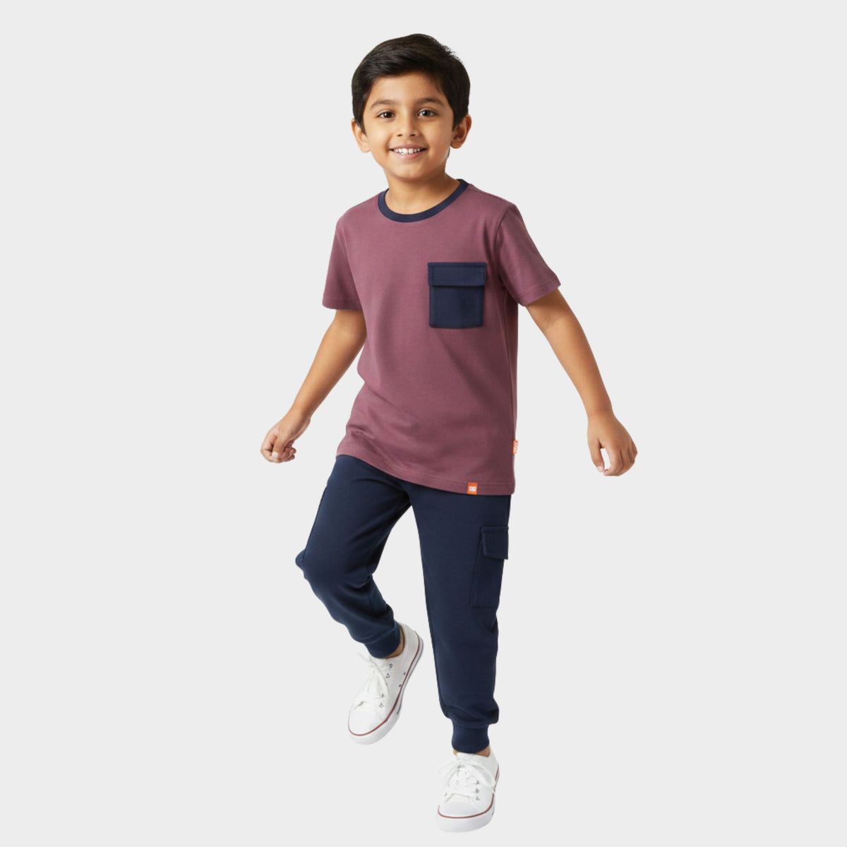 Child wearing a maroon shirt with a navy pocket and navy pants on a white background
