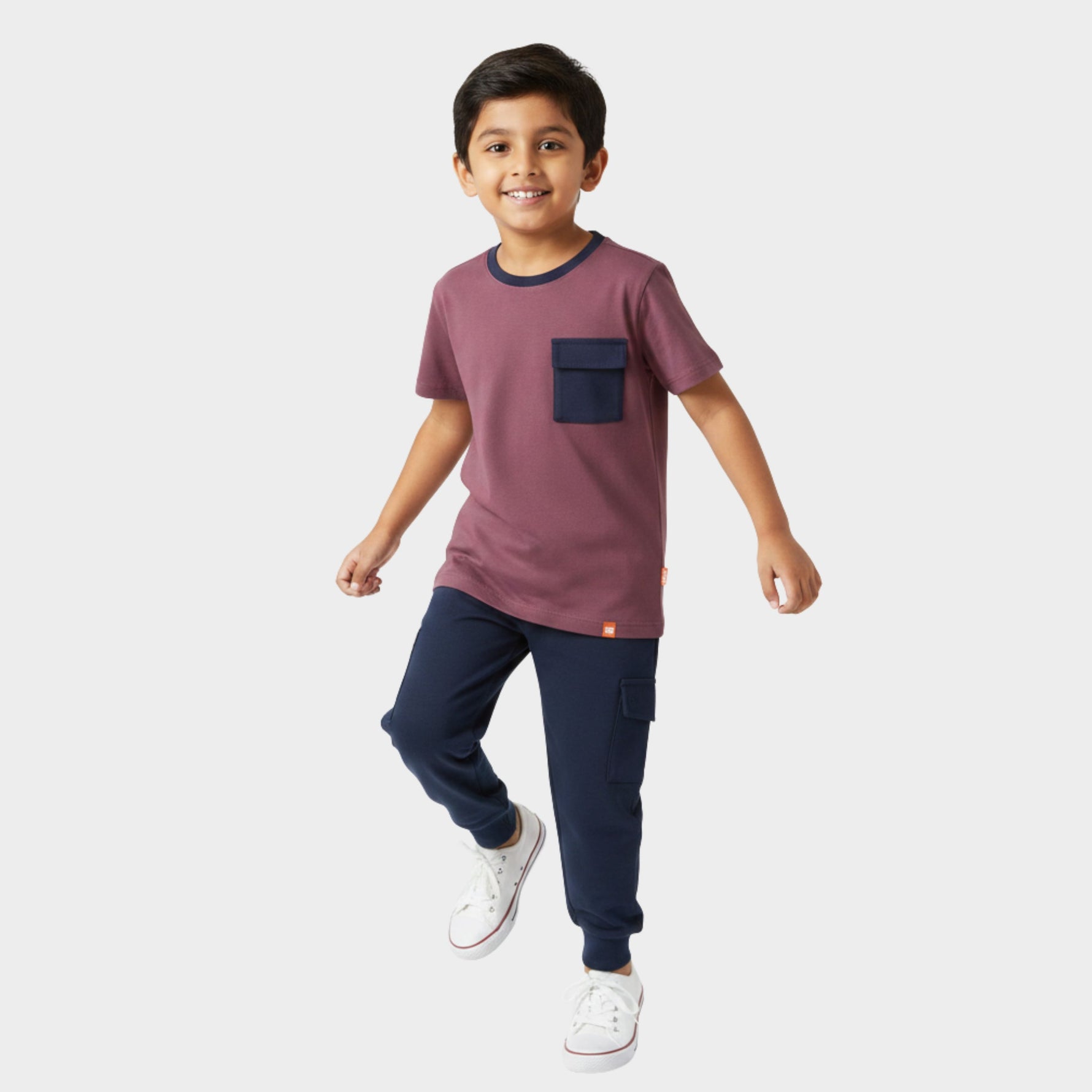 Child wearing a maroon shirt with a navy pocket and navy pants on a white background